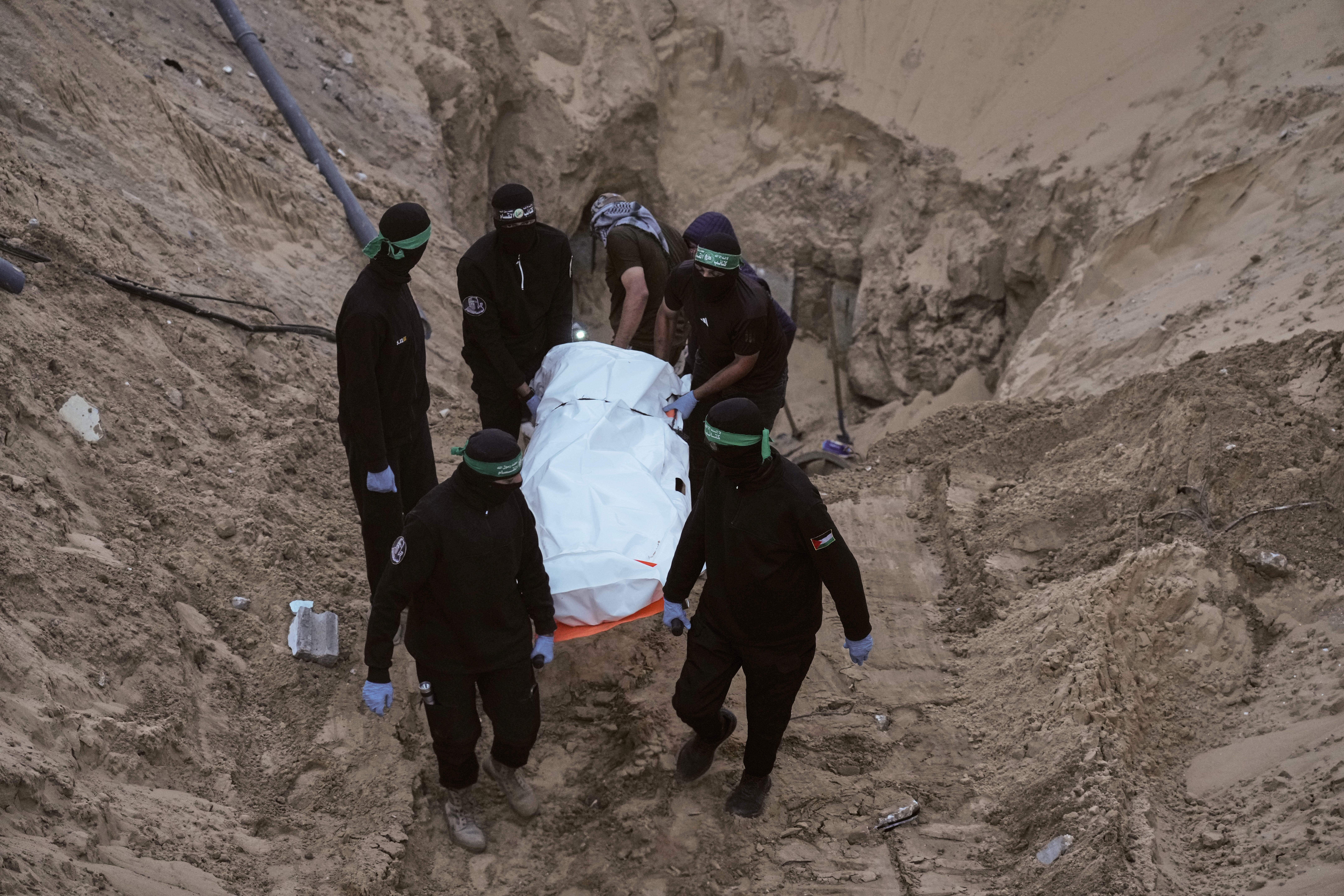 Hamas militants carry a white bag believed to contain a body, after retrieving it from a tunnel during a search for the remains of hostages in Hamad City, Khan Younis, in southern Gaza, Tuesday, Oct. 28, 2025.